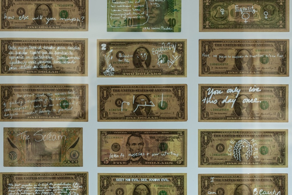 image of dollar bills with messages laser cut out of the paper